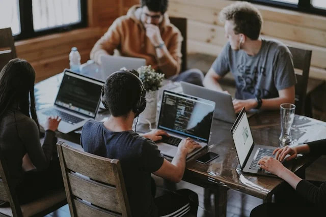 team of diverse creative developers collaborating in a bright modern open office with plants and minimalist furniture